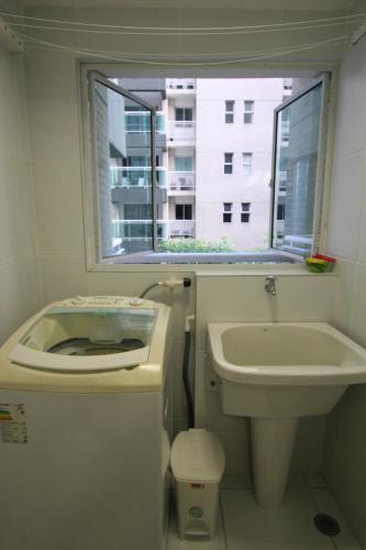 baño con lavabo y aseo y ventana en Apartamento NOVO Beira Mar JTR, en Maceió