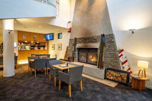 a lobby with a fireplace and tables and chairs at Heartland Hotel Queenstown in Queenstown