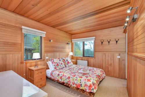a bedroom with a bed in a room with wooden walls at Snowgoose in Dinner Plain