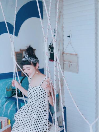 a woman in a polka dot dress sitting on a swing at Happiness Factory in Huxi