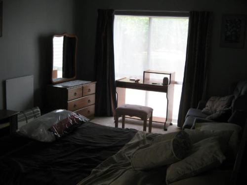 a bedroom with a bed and a desk and a window at The House in Christchurch
