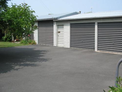 a garage with two garage doors and a driveway at The House in Christchurch