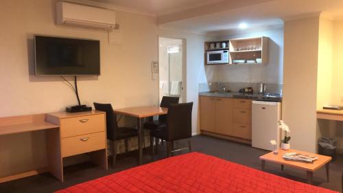 a small room with a kitchen and a table with chairs at Harbour City Motor Inn & Conference in Tauranga