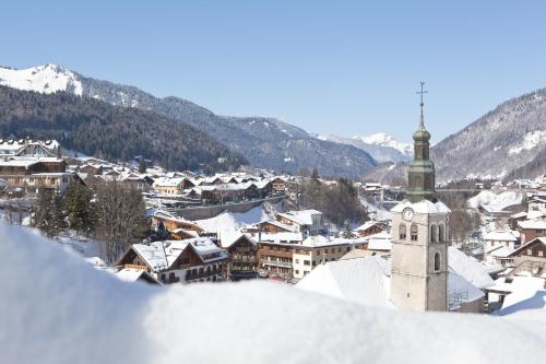 a town covered in snow with a church at Hotel le Petit Dru in Morzine