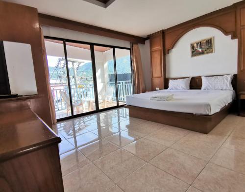 a bedroom with a bed and a large window at Praew Mansion in Kamala Beach
