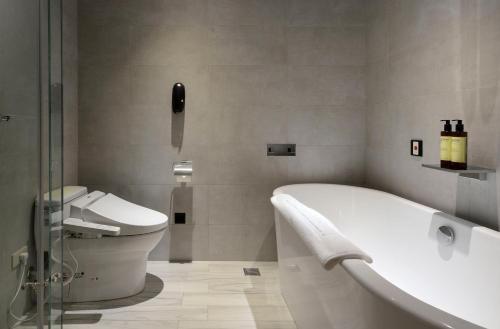 a bathroom with a bath tub and a toilet at Evergreen Palace Hotel Chiayi in Taibao
