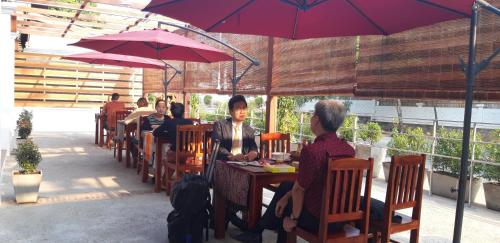 a group of people sitting at a table under an umbrella at Villa Chitchareune 2 in Luang Prabang