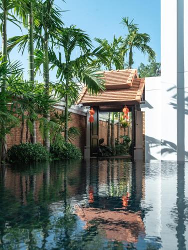 a house in the water with palm trees at El Barrio Lanna in Chiang Mai