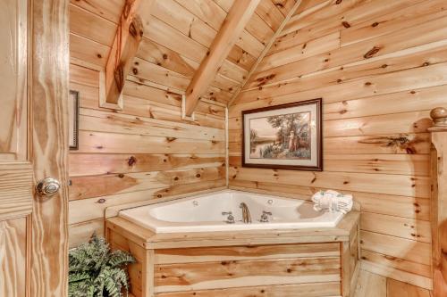 a log cabin bathroom with a tub and wooden walls at Above the Pines in Pigeon Forge