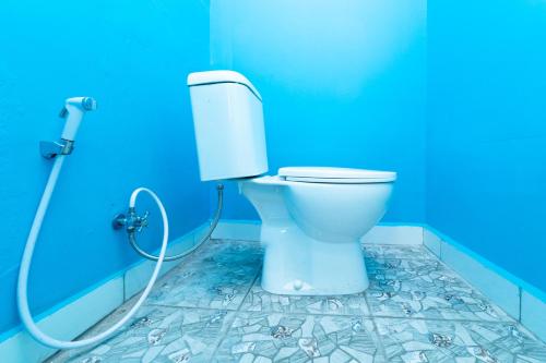 een badkamer met een toilet in een blauwe muur bij KoolKost At Menceng Raya - Minimum Stay 30 Nights in Jakarta