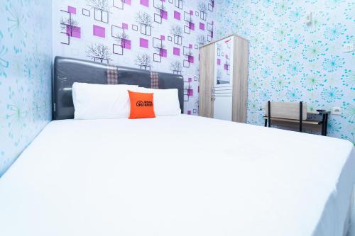 een slaapkamer met een groot wit bed en een oranje kussen bij KoolKost At Menceng Raya - Minimum Stay 30 Nights in Jakarta