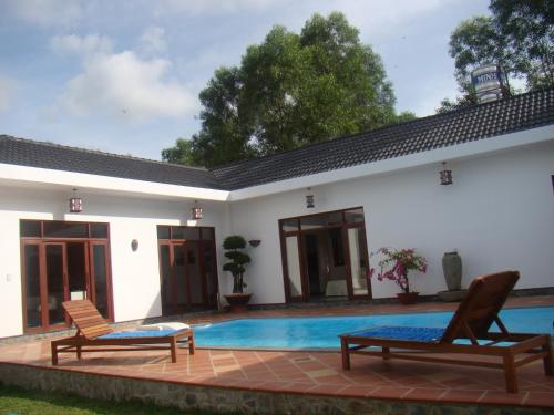 une villa avec une piscine et deux chaises dans l'établissement Phu Quoc Private Villa, à Duong Dong