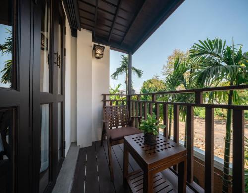 a porch with a table and a chair on a balcony at El Barrio Lanna in Chiang Mai
