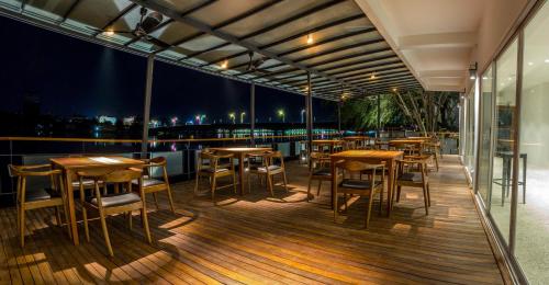 a restaurant with wooden tables and chairs on a balcony at The B Resort in Kampot