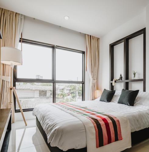 a bedroom with a large bed and large windows at Siamplaengna Residence in Bangkok