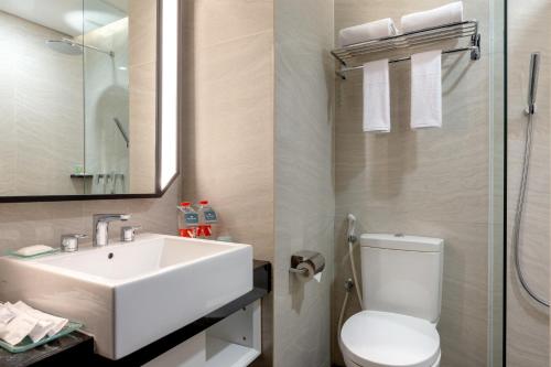 a bathroom with a white sink and a toilet at Hotel Santika Pasir Koja Bandung in Bandung