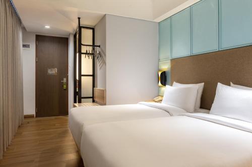 two beds in a hotel room with white pillows at Hotel Santika Pasir Koja Bandung in Bandung