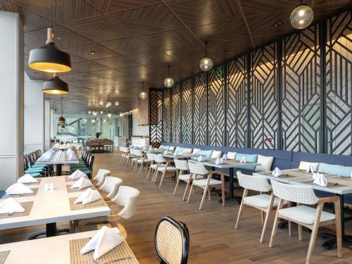 a dining room with tables and white chairs at Hotel Santika Pasir Koja Bandung in Bandung