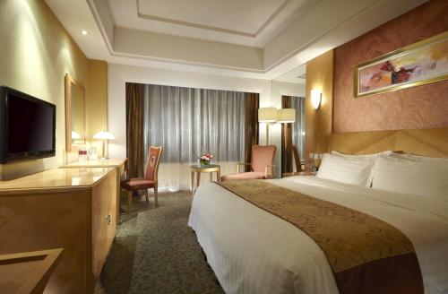 Dalian East Hotel في Jinzhou: غرفه فندقيه سرير كبير وتلفزيون