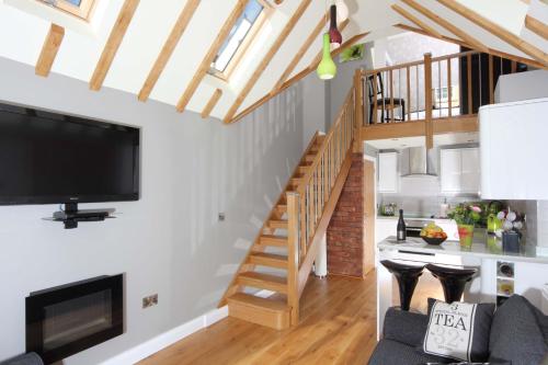 a living room with a staircase and a flat screen tv at Wenlock Studios in Much Wenlock