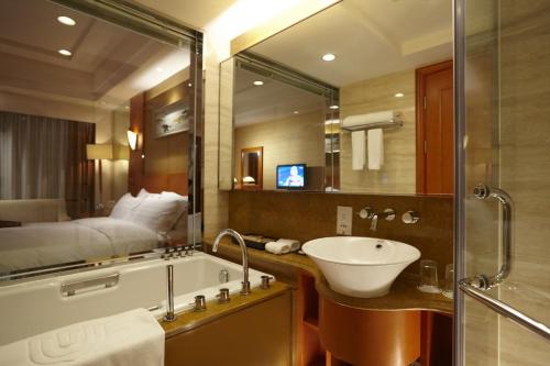 Dalian East Hotel في Jinzhou: حمام مع حوض ومرآة كبيرة
