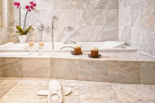 ein Badezimmer mit einer Badewanne und zwei Gläsern Champagner in der Unterkunft Arni Hotel Domotel in Kardítsa