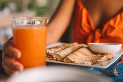 a person holding a plate of food and a glass of orange juice at Sevanagama in Habarana