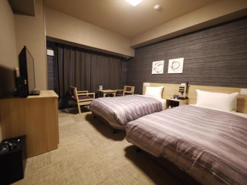 a hotel room with two beds and a television at Hotel Route-Inn Wajima in Wajima