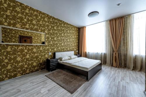 a bedroom with a bed and a wall with gold wallpaper at Hotel Azia in Perm