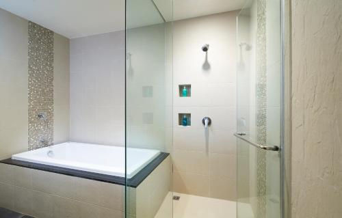 uma casa de banho com uma cabina de duche em vidro e uma banheira. em Shama Sukhumvit Bangkok em Bangkok