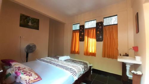 a bedroom with a bed in a room with windows at Made Roejas Family in Uluwatu