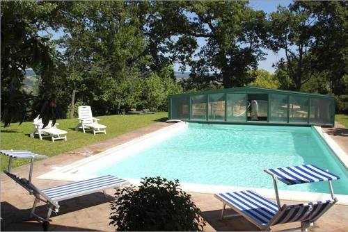 a swimming pool with two chairs and a house at Villa Podere Isabella in Radicofani