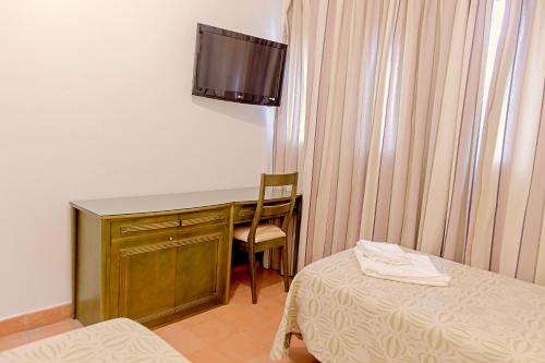 
a hotel room with a bed and a television at Lantana Garden in Pilas
