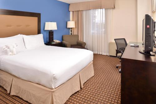 a hotel room with a large bed and a television at Ramada Plaza by Wyndham Sheridan Hotel & Convention Center in Sheridan