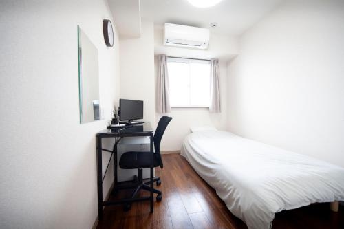 a bedroom with a bed and a desk with a computer at Hotel Chuo Crown in Osaka