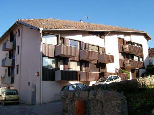 un bâtiment avec balcon et voitures garées dans un parking dans l'établissement studio ensoleillé, à Gérardmer