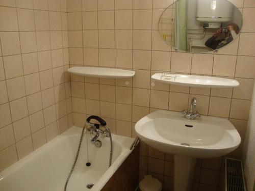 Baño de azulejos blancos con lavabo y bañera en studio ensoleillé, en Gérardmer