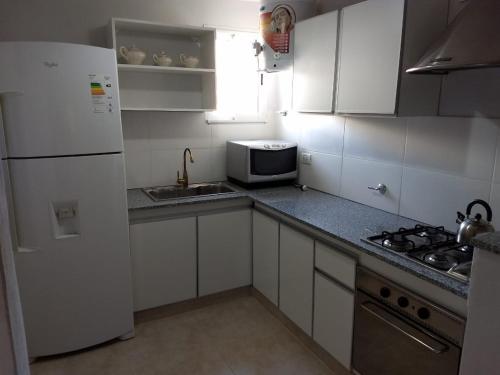 a kitchen with white cabinets and a sink and a microwave at El chalecito de Marta (PH) in Necochea