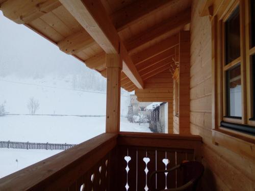 a porch of a wooden cabin with a snow covered yard at Schlosswirt Chalets & Apartments in Großkirchheim