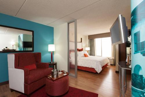 a hotel room with a bed and a chair and a mirror at Hotel Indigo Chicago - Vernon Hills by IHG in Vernon Hills
