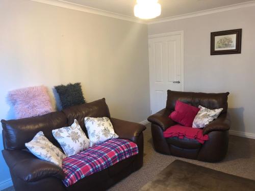 a living room with two leather chairs and a couch at PondeROSEa Cottage Free Gated Parking M1 & City location, wood stove in Lisburn