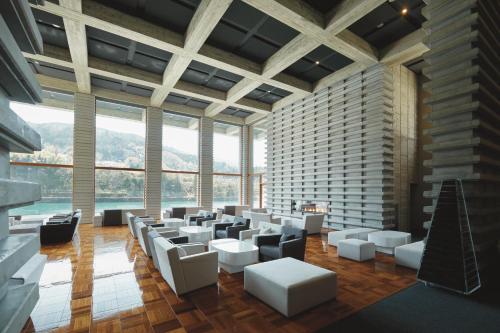 a large room with white furniture and large windows at River Retreat Garaku in Toyama