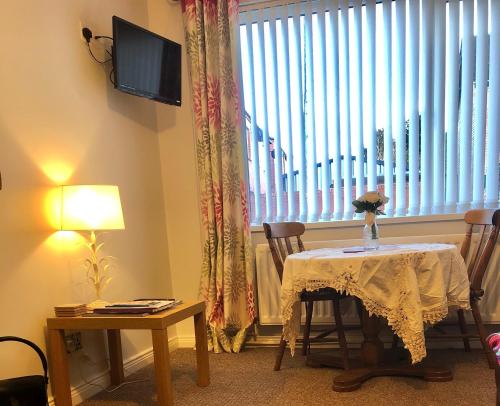 a living room with a table and a large window at PondeROSEa Cottage Free Gated Parking M1 & City location, wood stove in Lisburn