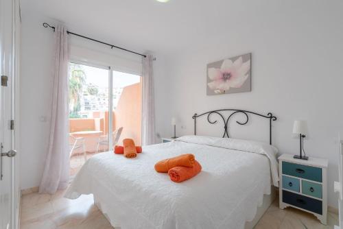 ein weißes Schlafzimmer mit einem Bett mit orangefarbenen Handtüchern darauf in der Unterkunft Apartamento Ibn sadi14 in Nerja