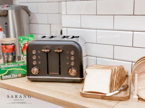 a toaster sitting on a counter next to a slice of bread at Sarang Hostel at City Centre in Kota Kinabalu