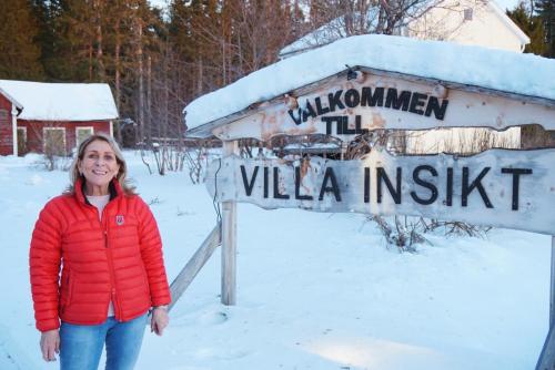 a woman standing next to a sign in the snow at Villa Insikt Pensionat & Kursgård in Burträsk