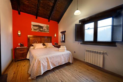 a bedroom with an orange wall with a bed and a window at Hotel Tejera del Nalon in Soto del Barco