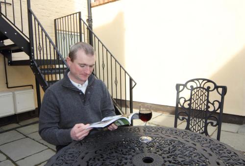 a man sitting at a table reading a book and a glass of wine at Brookes Holiday Let in Much Wenlock