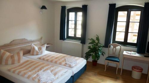 a bedroom with two beds and a chair and windows at MB Hotel Weißer Hirsch in Hohnstein