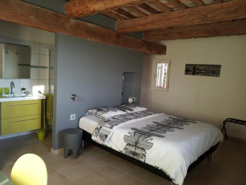 a bedroom with a large bed and a kitchen at Le Grangeon in Cruis